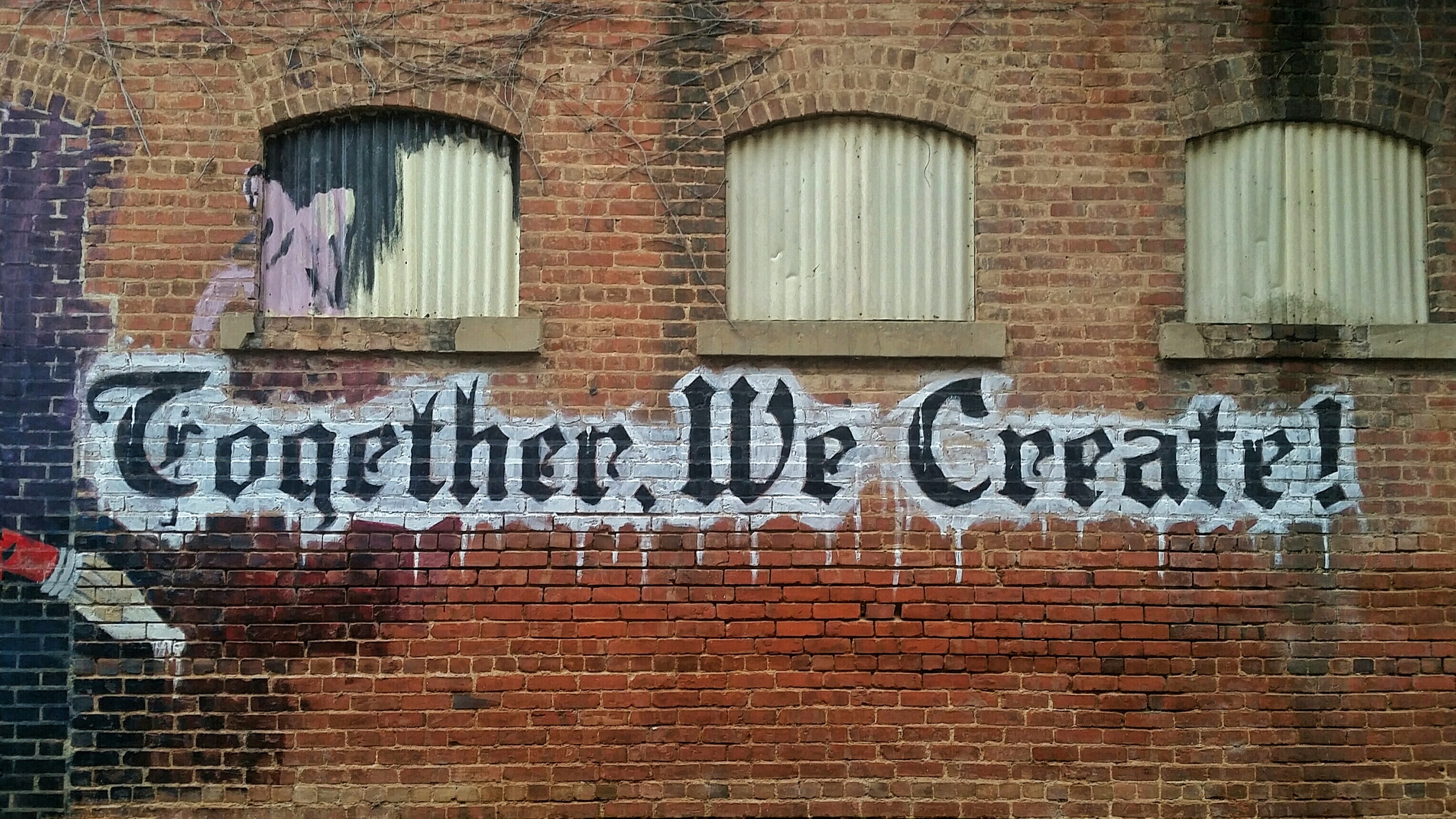 "Together, we create!" on a brick wall