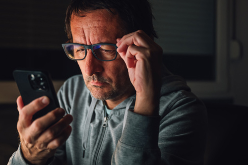 Man on phone while touching glasses