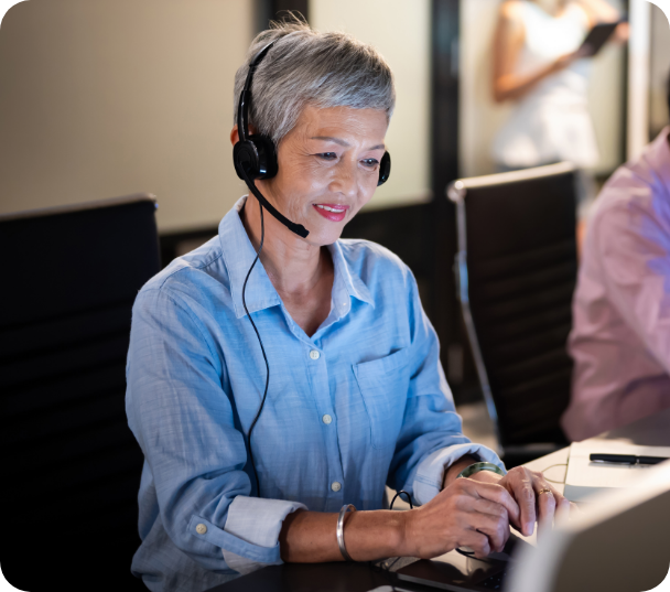 Older woman smiling while working at a computer.