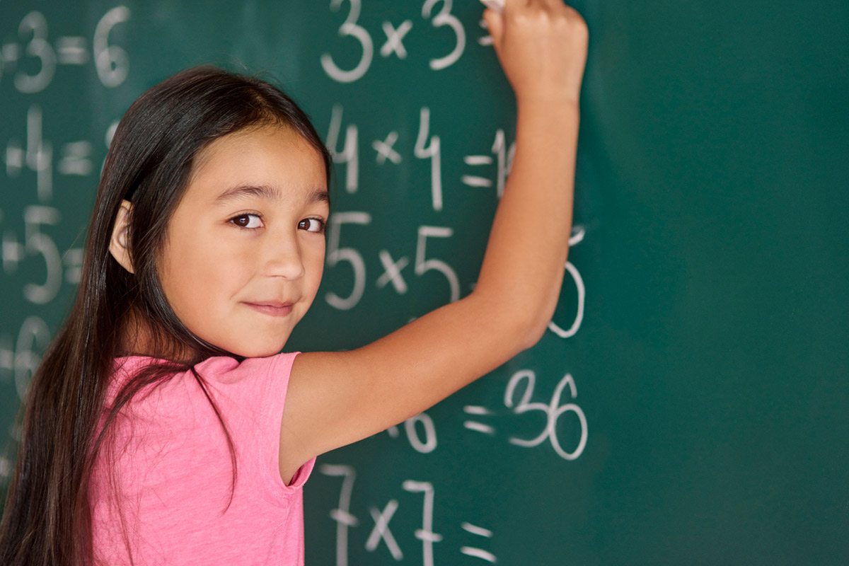 Elementary aged girl writing on a chalkboard