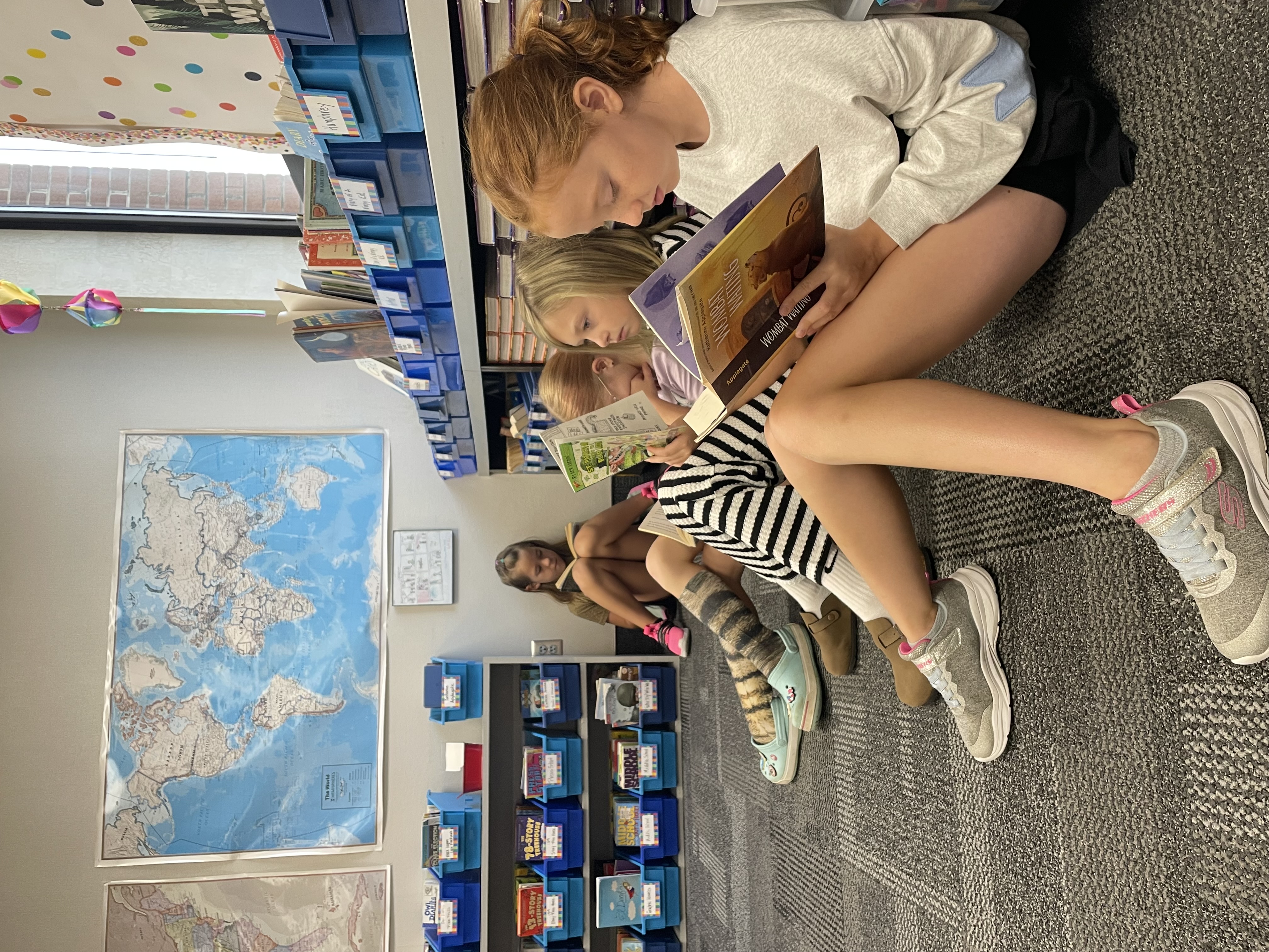 Students readings book intently on the floor