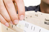 A close-up shot of fingers flicking through a file folder.