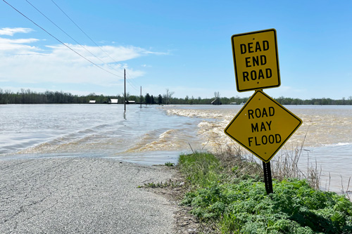 Road May Flood sign in front of flood waters covering road
