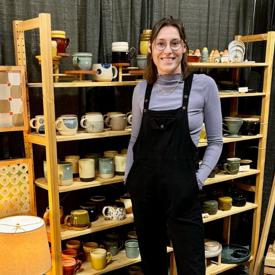 Woman standing in front of shelves holding ceramics