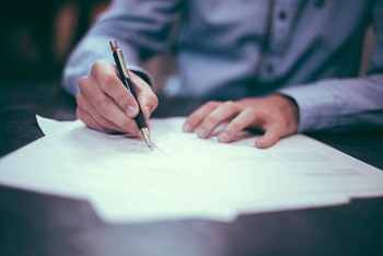 Person writing with pen on papers