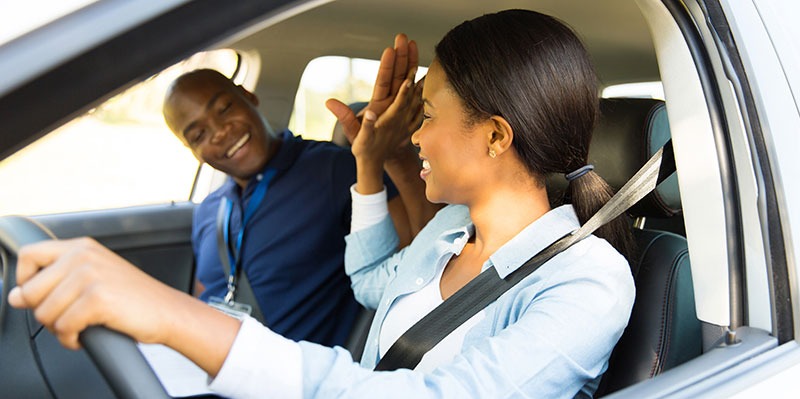 young female driver giving a high five to her driving instructor