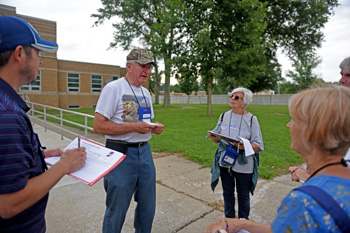 Group with clipboards interviews man