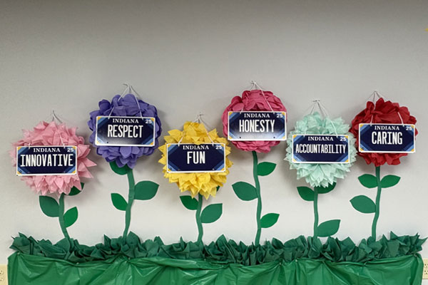 Wall display of BMV's Core Values with flowers in grass