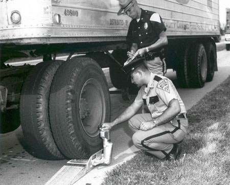 Corporal Bruce Hubble looks on as unknown weigh clerk checks the weight on the portable scale.