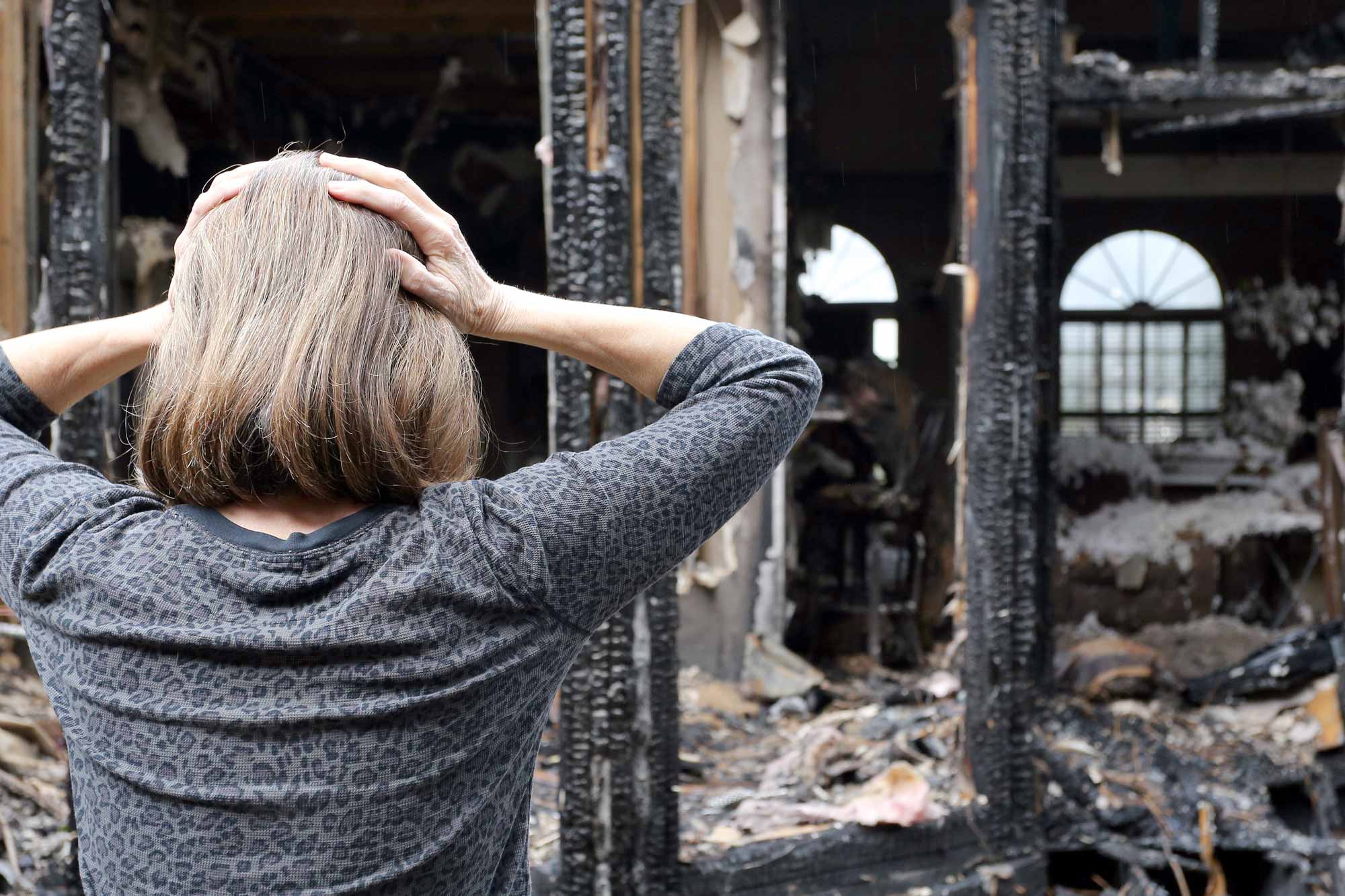 Woman looks at debris from house fire