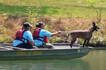 Two people on boat with dog on leash