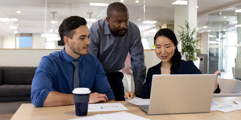 diverse of employees looking at documents and a laptop