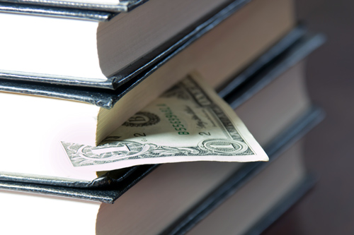 Money sticking out of stack of books