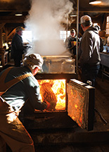 Bob Rennick loads wood into the evaporator as sap boils down to maple syrup at Gray Woods Sugar Camp.