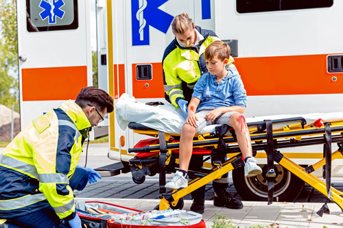 Child sits on gurney outside ambulance as EMS workers treat his injuries Child sits on gurney outside ambulance as EMS workers treat his injuries