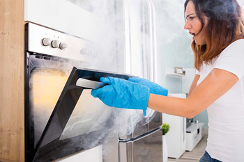 Women opening oven filled with smoke