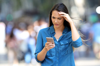 Woman looking troubled holding a cell phone