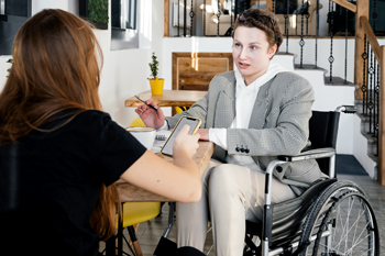 Woman in wheelchair having conversation at table with friend