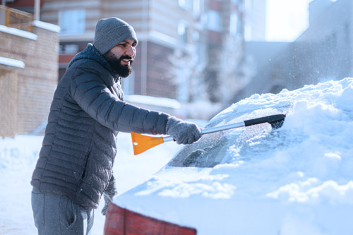 Man wiping snow off car window