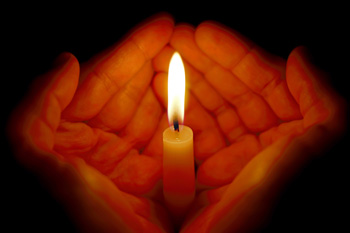 Hands wrapped around candle flame