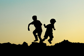 Children playing at sunset, silhouetted