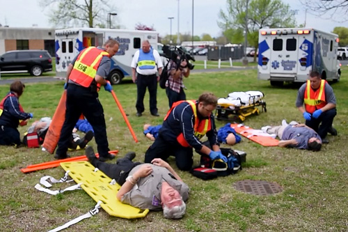 EMS personnel tend to victims on grass outdoors