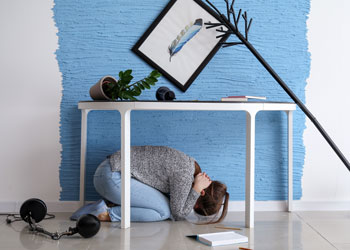 earthquake, woman covering neck, objects falling