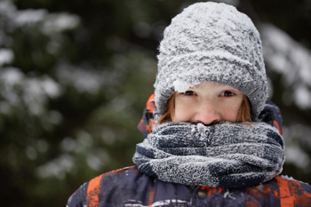 Person bundled in snow with scarf, hat