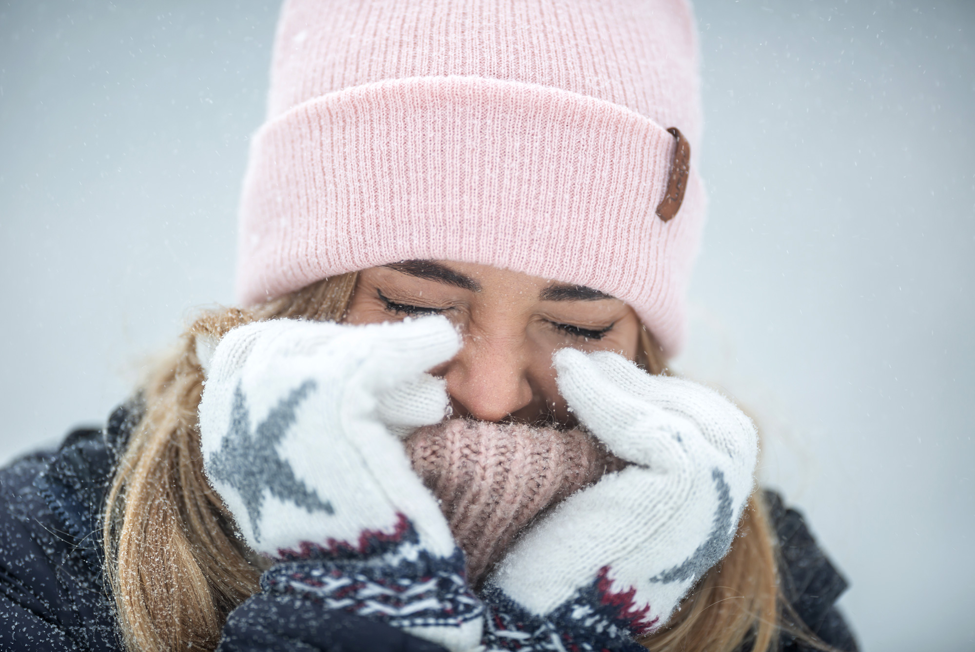 Woman bundled in warm clothes outside cringing