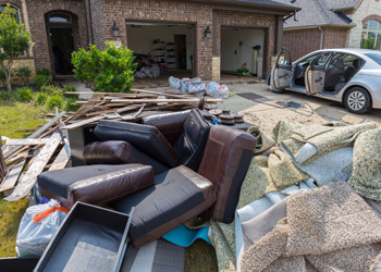 Flood-damaged couch and carpet on front lawn