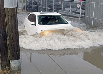 Car drives into flooded street with water over hood