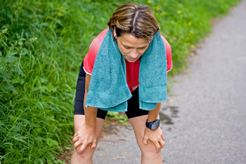 Exerciser bending over with wet towel around neck