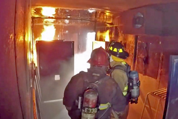 Firefighters inside live fire training trailer with flames