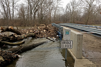 Log jam of debris at bridge with high waters