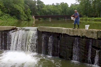 Man casting net over low-head dam