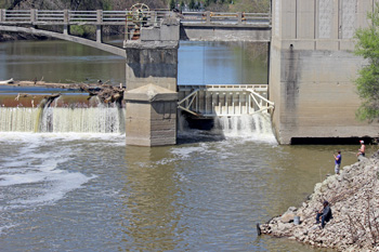 Low-head dam with bridge, flood gate, fishermen on bank nearby