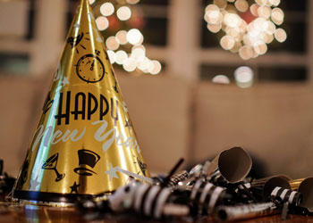 An assortment of New Year's Eve accoutrements including hat, glitter, ribbon, glass and bottle