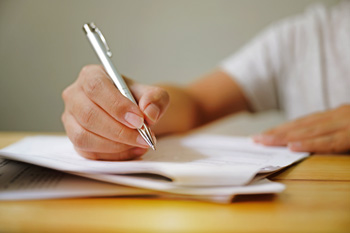 Person holding a pen to a packet of papers