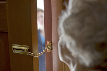 Woman peaking through door with chain lock at visitor