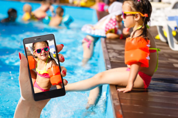 Mother holding phone photo of daughter in swimsuit