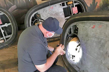 Inspector checking bottom of bumper car with flashlight