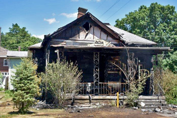 Burned-out house with high shrubs at foundation