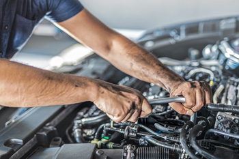 Mechanic holding a part under car hood