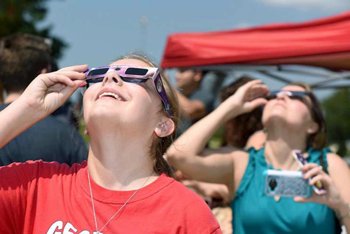 Women using eclipse glasses to look at sun