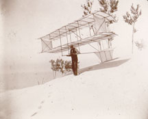 
  Chanute holds his biplane glider with side panels in August 1896 (Chanute photo album, Manuscript Division, Library of Congress).
  