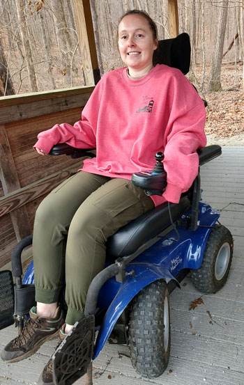 Women in motorized wheel chair in woods.