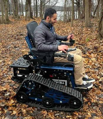 Man in motorized trail chair in woods.