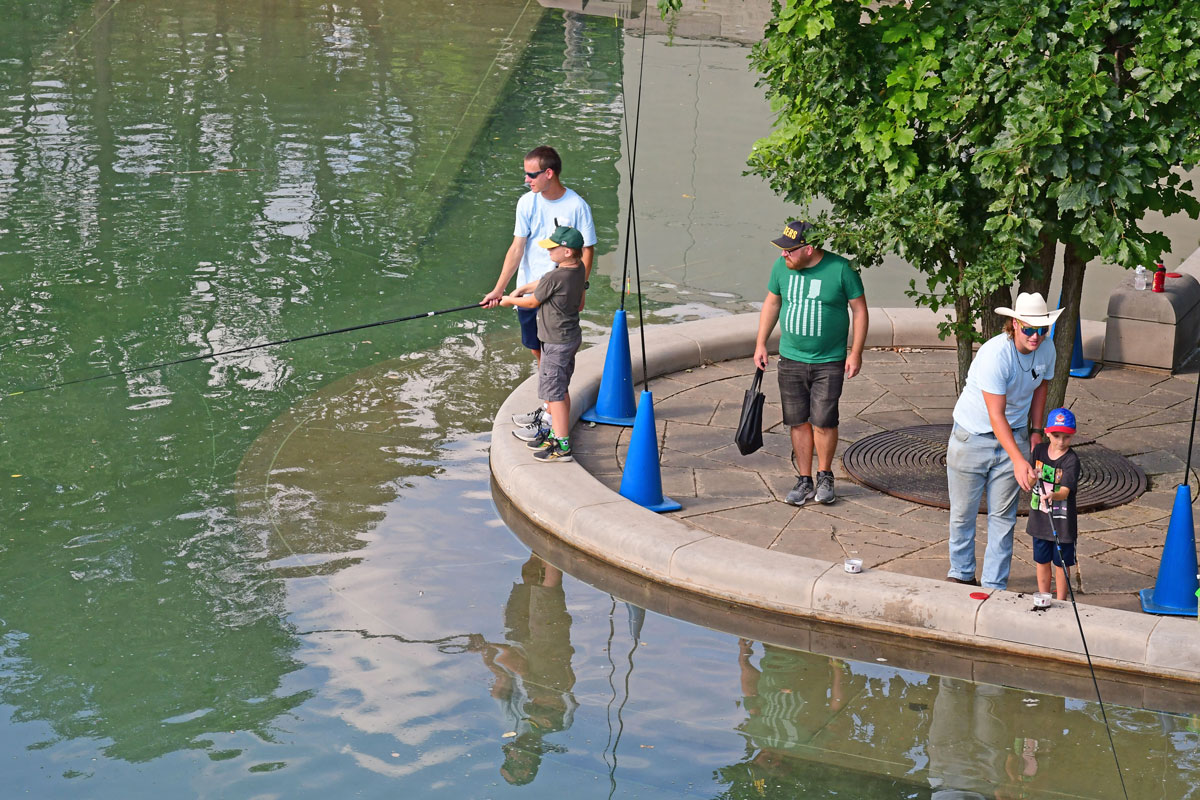 People fishing from concrete sidewalk.