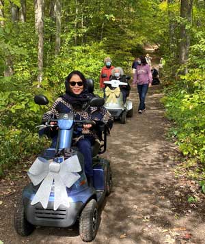 Women in motorized chairs on a trail.