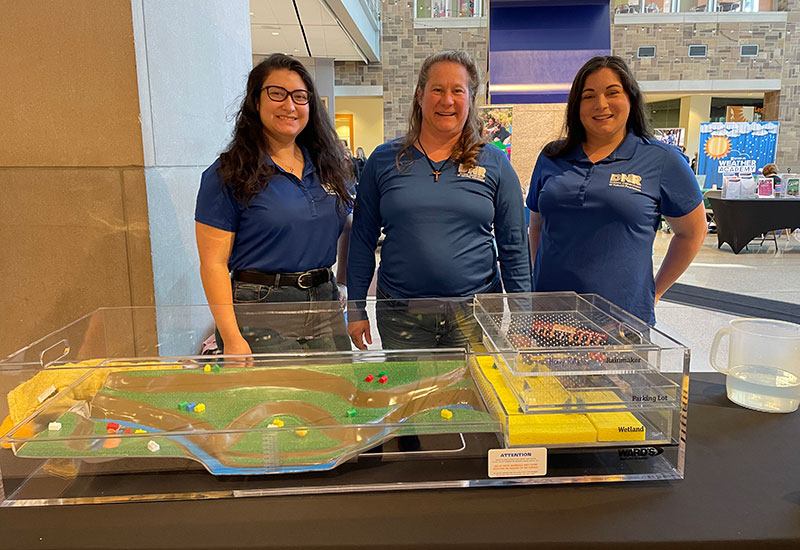 Three woman standing by a tabletop model